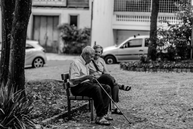 BPC e aposentadoria: principais diferenças que o cidadão precisa conhecer 6 A happy senior couple sitting on a bench, enjoying the outdoors in black and whi