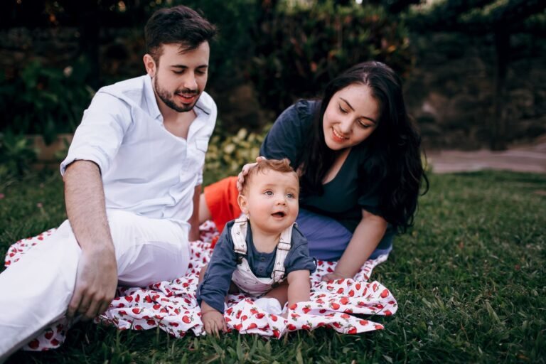 A joyful family enjoying a picnic outdoors during summer. Smiling parents with t