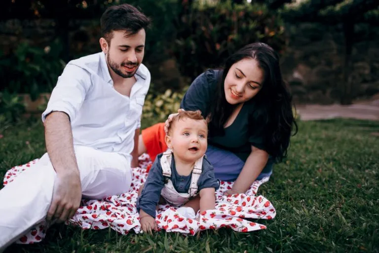 A joyful family enjoying a picnic outdoors during summer. Smiling parents with t