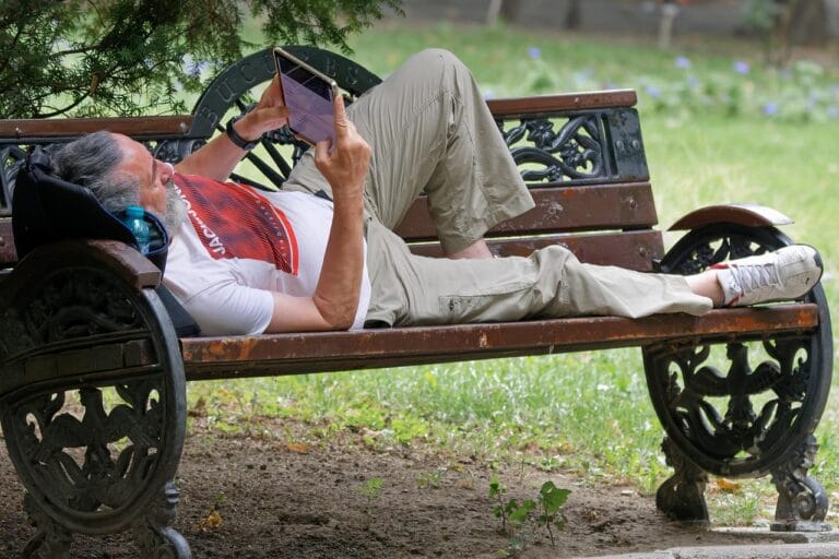 man, elderly, lying, bench, outdoors, parka, naturally, looking, tablet, relaxat