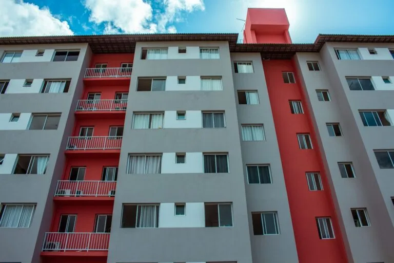 A high-rise residential building featuring a striking red facade and balconies a
