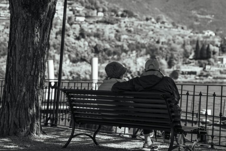 Serene moment of an elderly couple on a bench overlooking Lake Como.