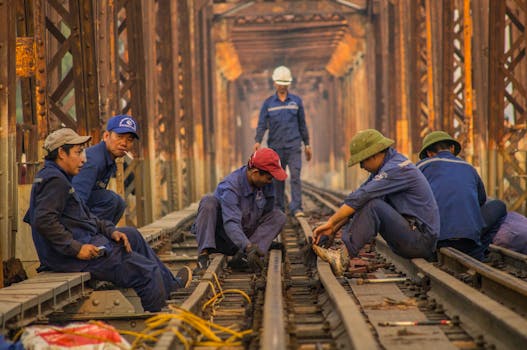 Group of workers maintaining railway tracks inside a rusty old bridge