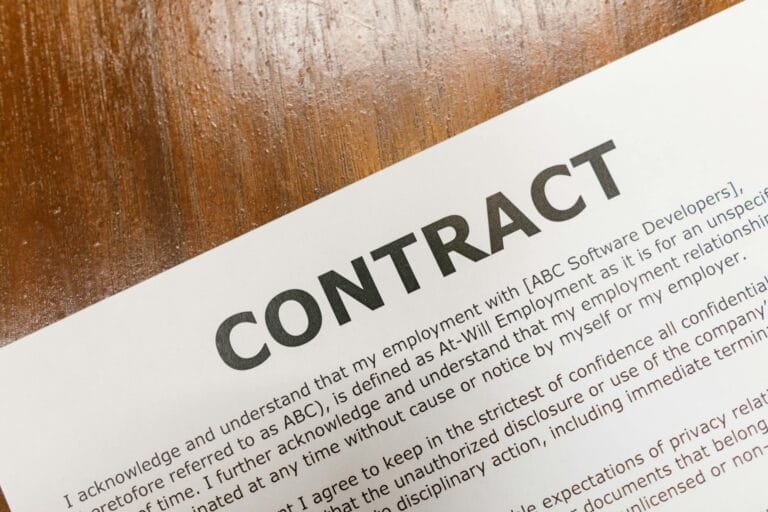 A detailed close-up of a printed contract document on a wooden table surface.