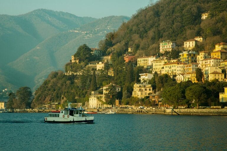 Picturesque view of Lago di Como with colorful hillside houses and a ferry in sp