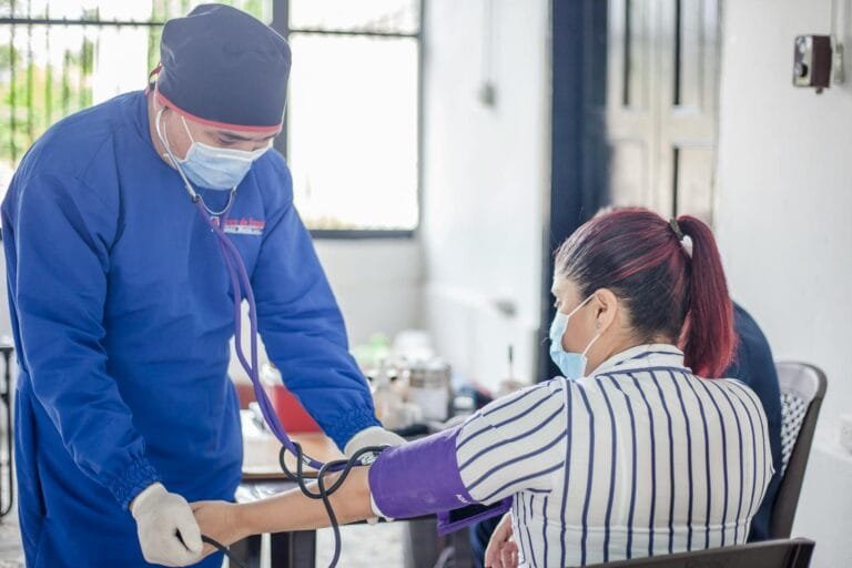 A nurse performs a blood pressure check on a patient in a healthcare setting, emphasizing safety and care.