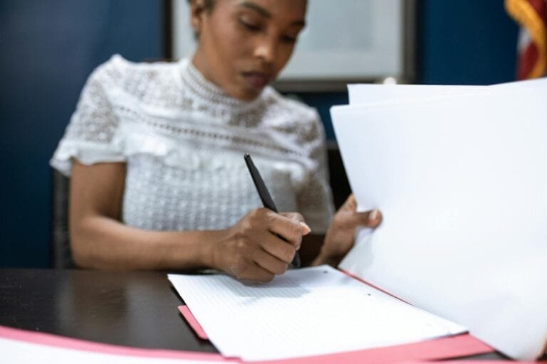 African American woman signing documents in an elegant office setting, showcasing leadership.
