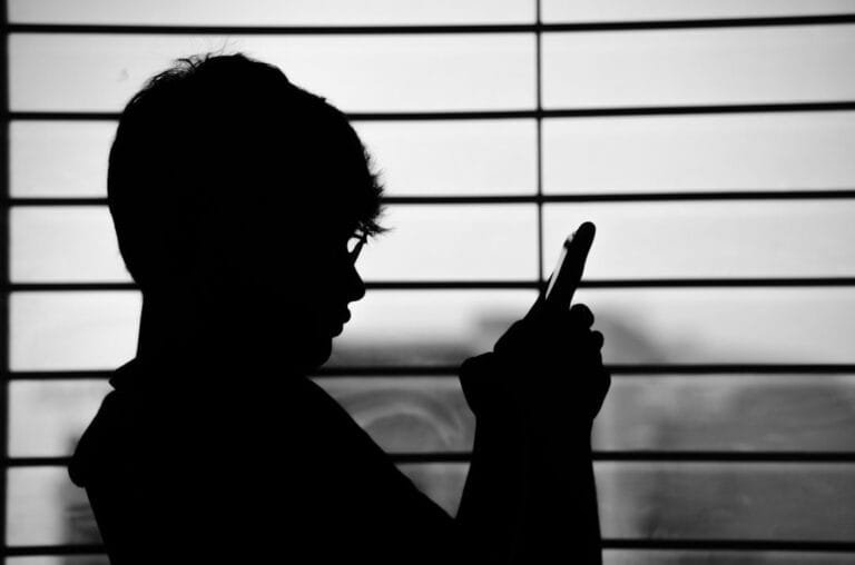 silhouette of man wearing eyeglasses and holding phone
