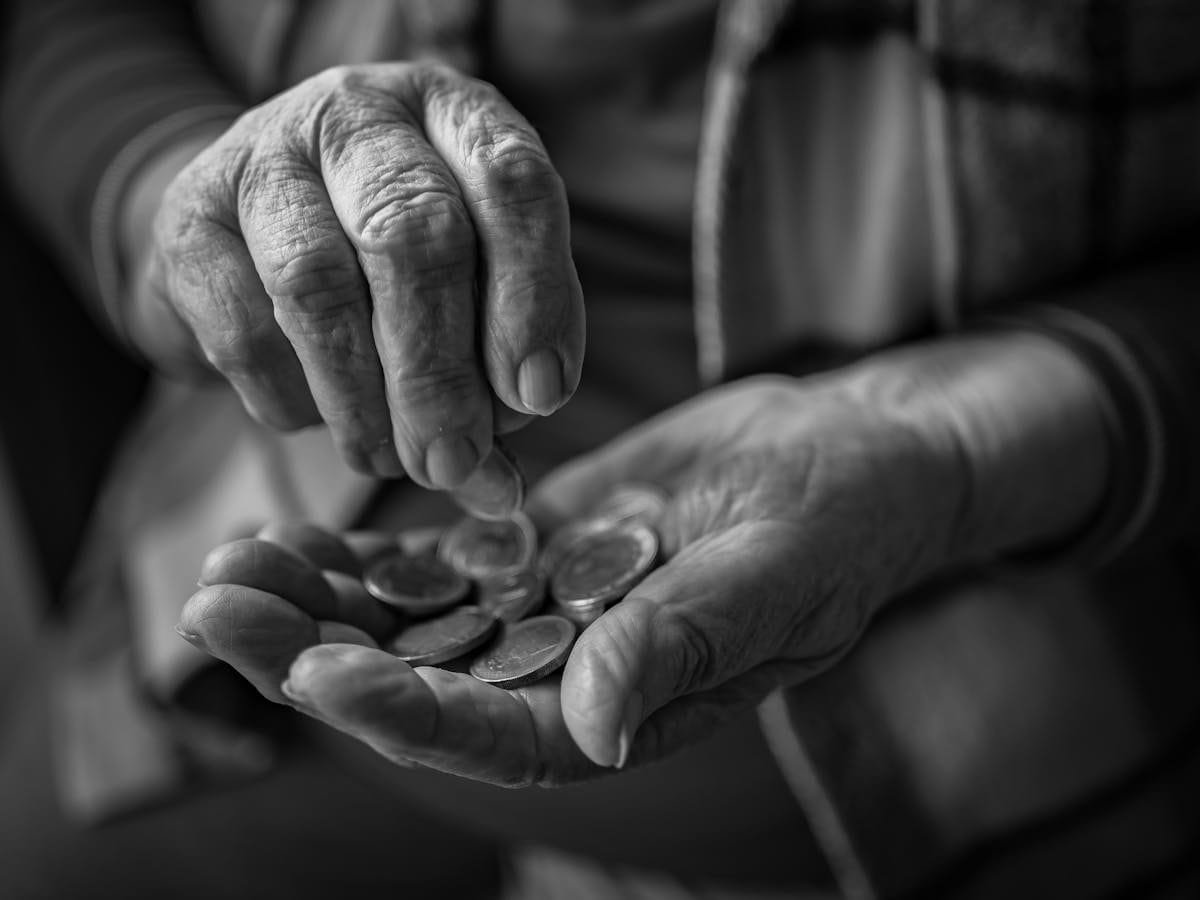 Aposentadoria Especial: Atividades Insalubres e Conversão de Tempo 1 A close-up of elderly hands counting coins, portraying poverty and financial insecurity.