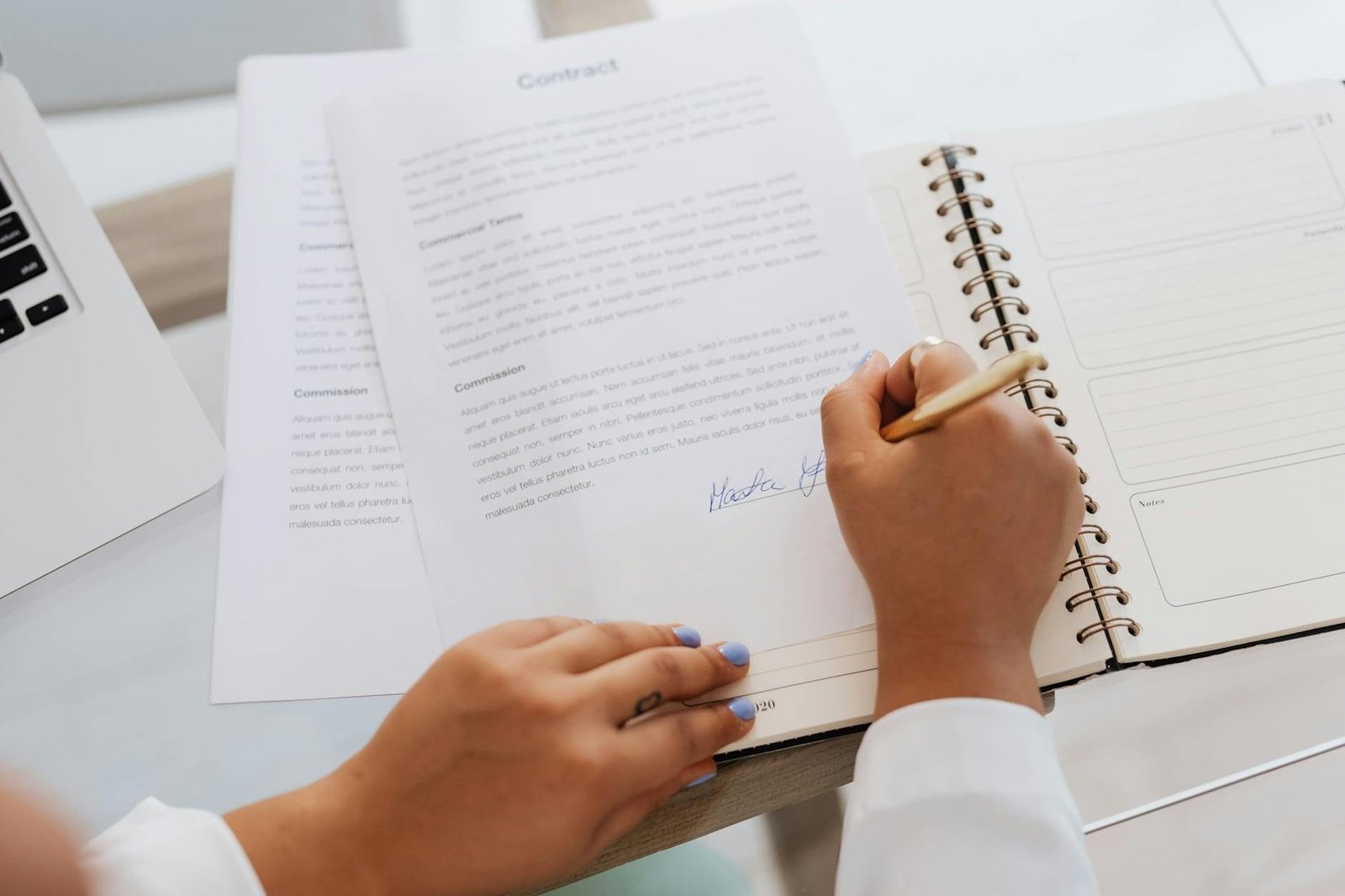 Pessoa assinando contrato de consórcio sobre a mesa de trabalho