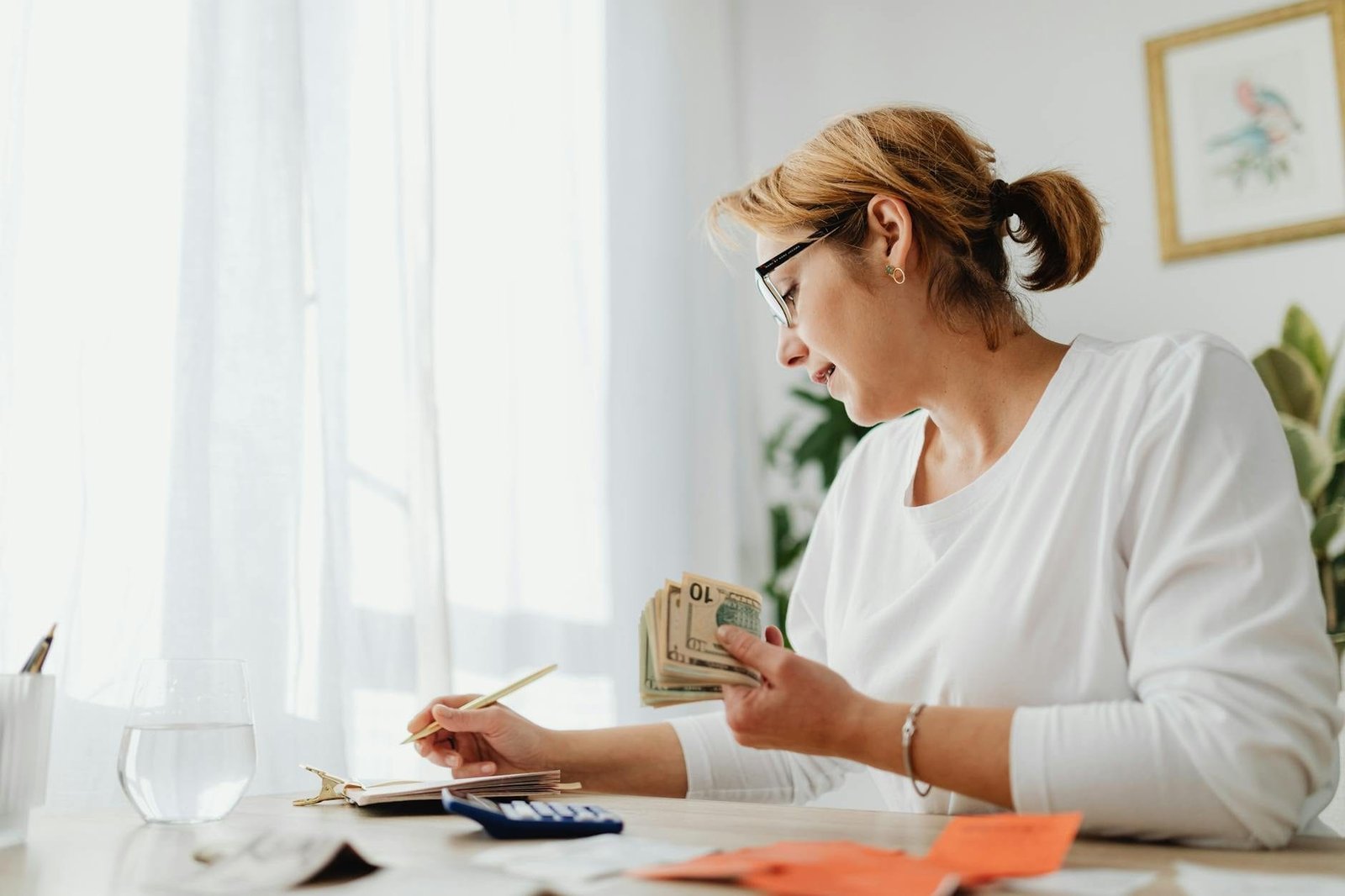 Mulher calculando contribuição acima do teto do INSS com calculadora e dinheiro