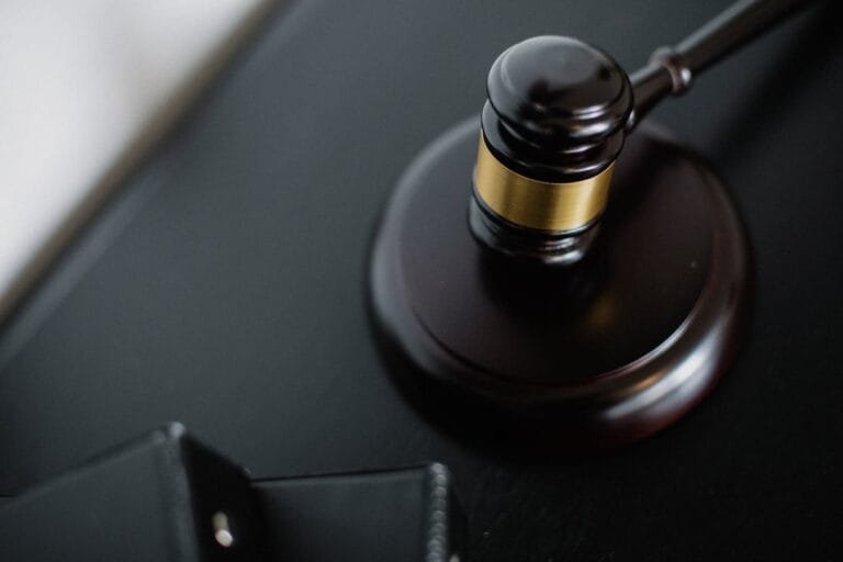 From above of wooden gavel on round surface near folders on table in courtroom