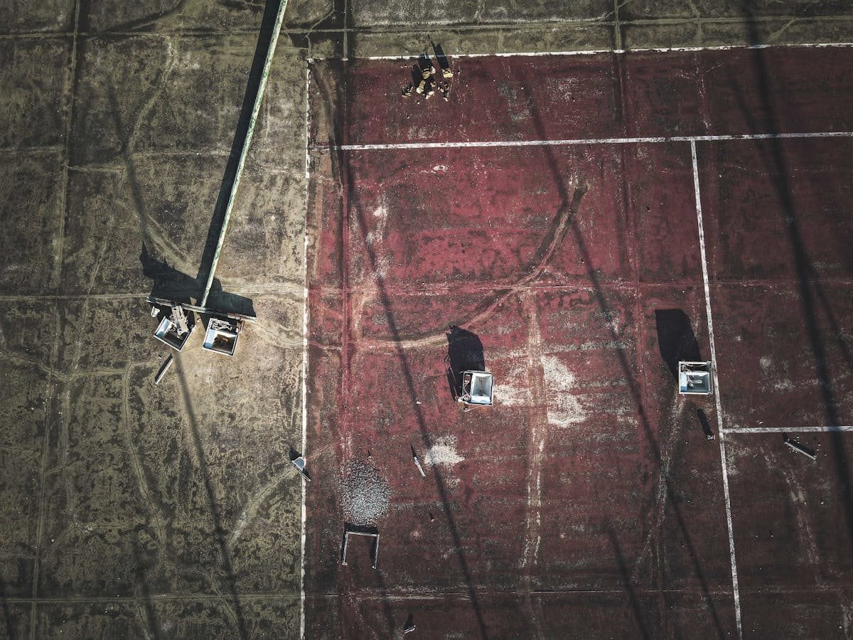 From above of broken streetlamps scattered on shabby old dirty sports ground on sunny day
