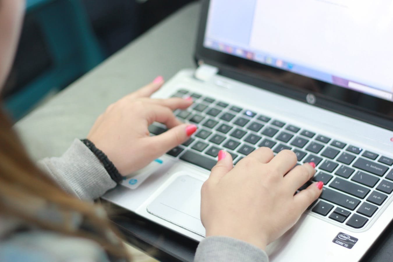 Close-up view of hands typing on a laptop keyboard, focusing on digital work.