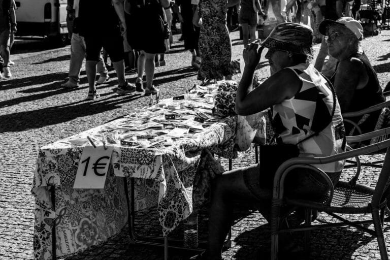 Black and white photo of people at a street market in Porto, Portugal, selling g