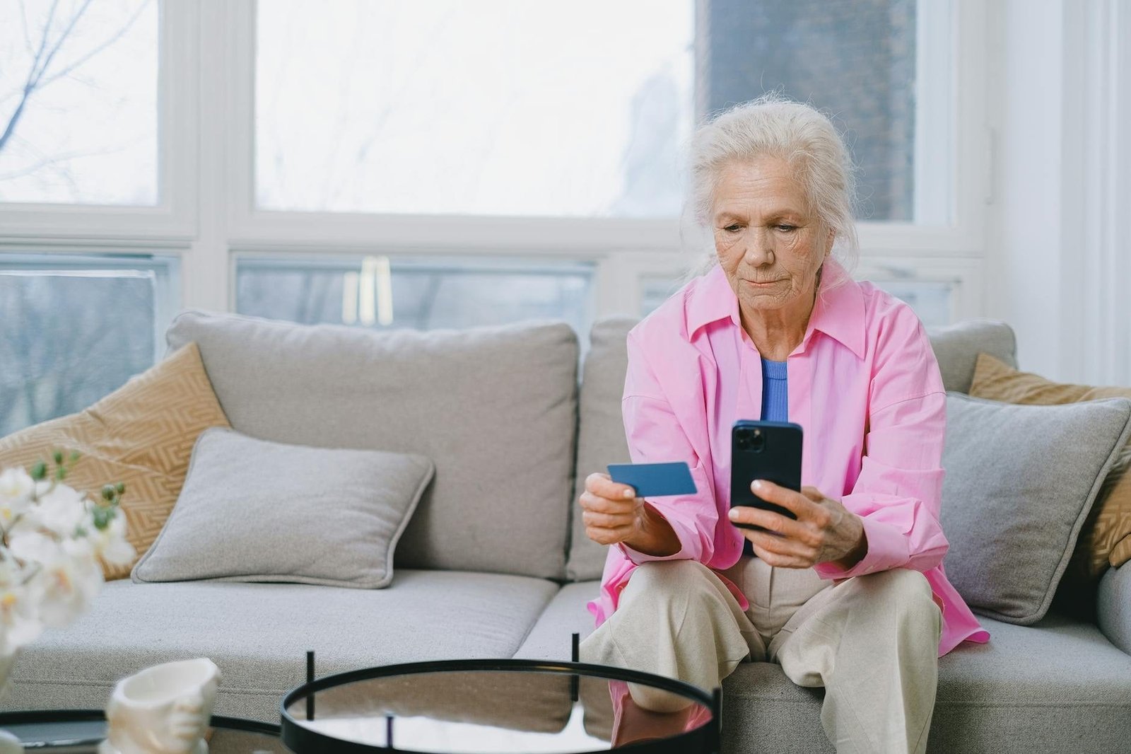 BPC LOAS para Idosos e Pessoas com Deficiencia: Criterios e Como Solicitar 1 Elderly woman shopping online using smartphone and credit card indoors.