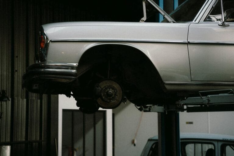 Auto de Infração: Como Apresentar Impugnação e Recurso 5 A classic car is elevated on a lift in a professional auto repair garage, showca