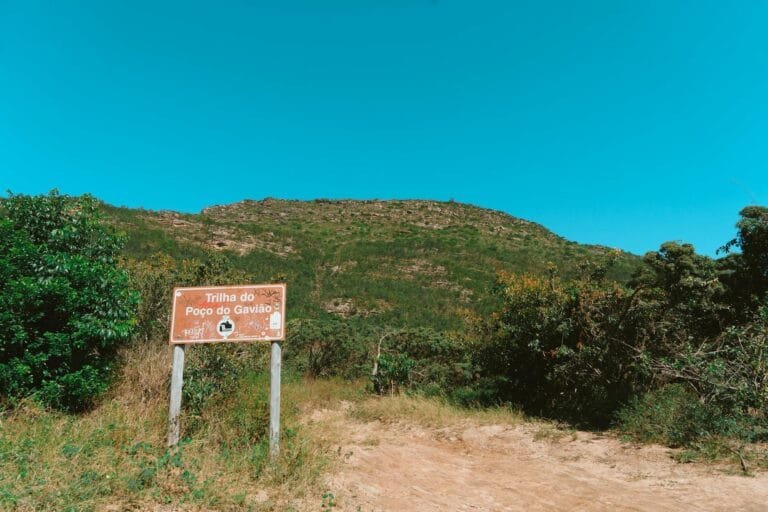Explore the lush hiking trail of Poço do Gavião under a clear blue sky.