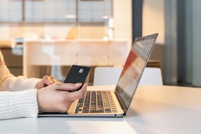 A woman using a credit card and laptop for online shopping in a modern indoor se