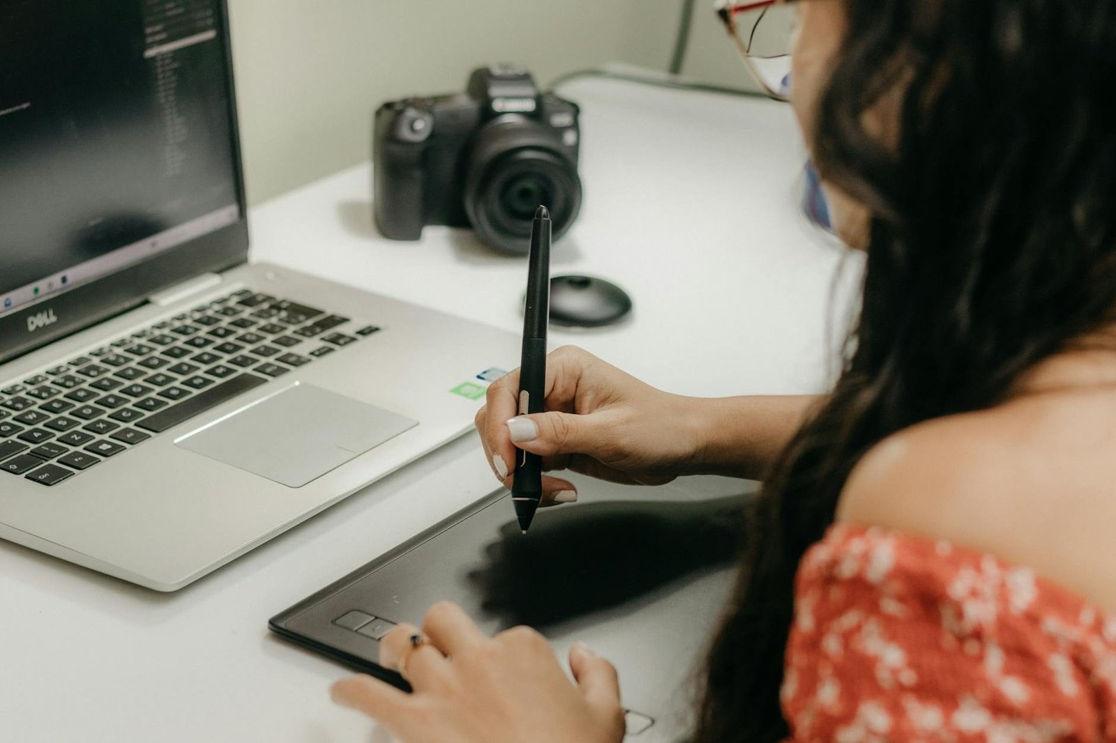 A woman using a digital tablet and stylus next to a laptop, showcasing modern de