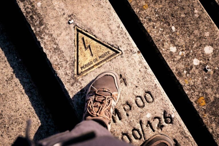 Foot on concrete slab with electrical warning sign in Portuguese.