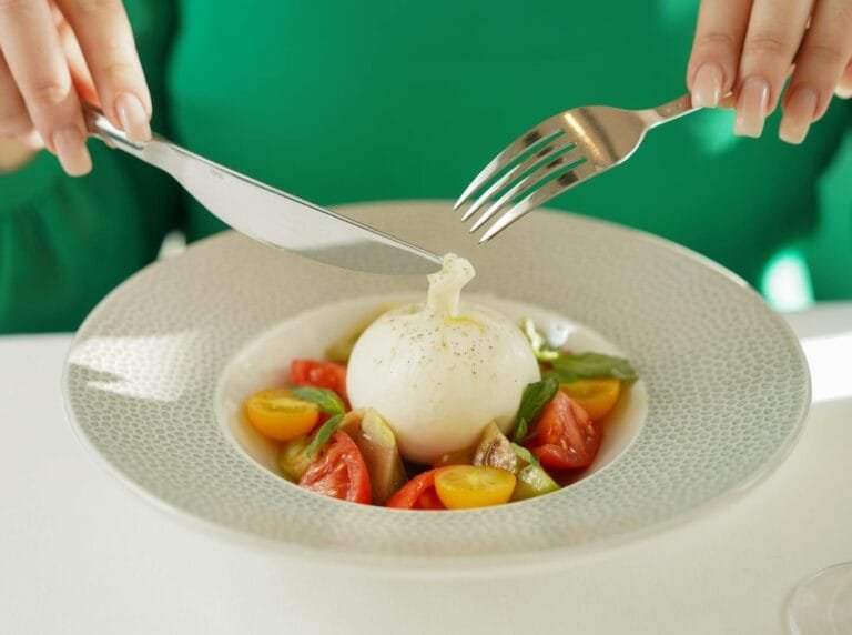 A vibrant close-up of burrata salad being enjoyed with fresh tomatoes and basil.