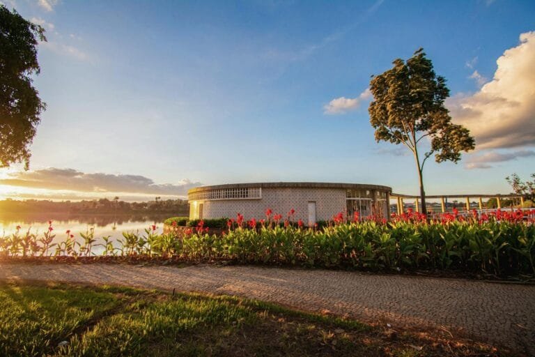 Beautiful sunset at Pampulha Lake with architectural building and lush gardens.