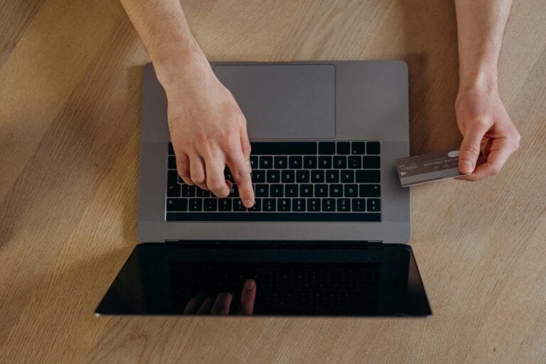 Top view of hands using a credit card and laptop for online transactions on a wo