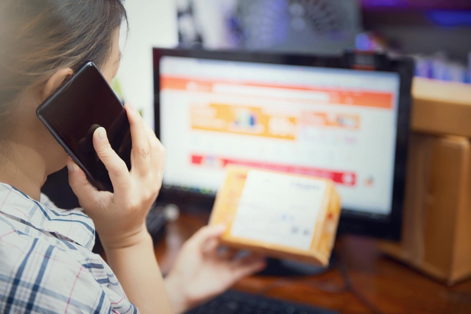 Woman multitasking by using a phone and checking an online purchase package at h