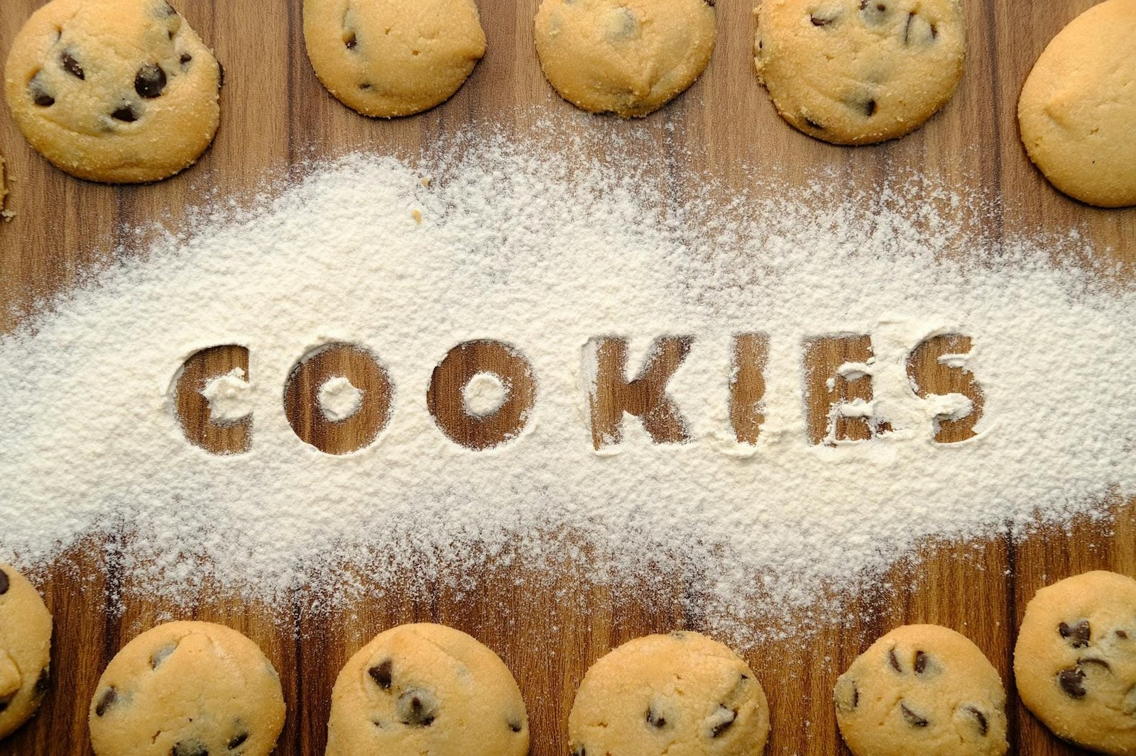 Cookies e Consentimento: Como o Site Deve Tratar os Dados do Visitante 1 Freshly baked chocolate chip cookies arranged on flour-dusted wooden table.