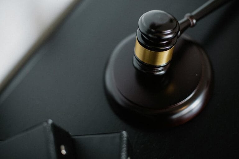 From above of wooden gavel on round surface near folders on table in courtroom