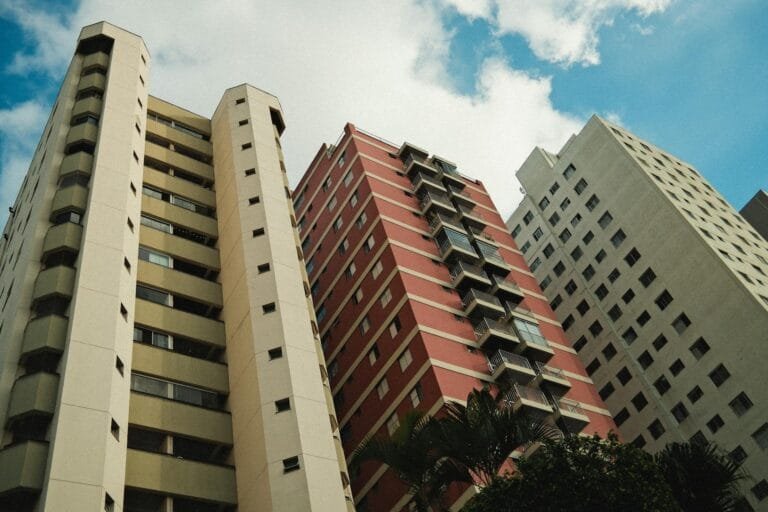 A low-angle view of three high-rise buildings with diverse architecture under a 