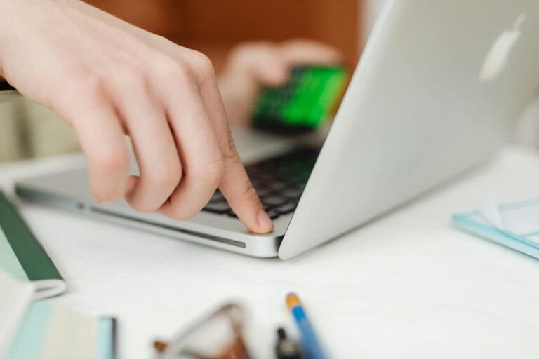 Close-up view of hands operating a laptop while holding a credit card, showcasin
