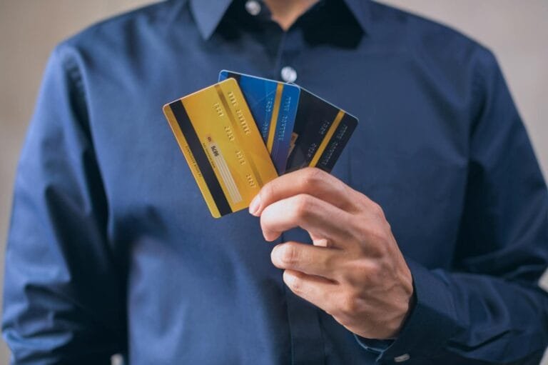 Credito Tributario: Lancamento, Suspensao, Extincao e Exclusao 3 Person holding three credit cards, symbolizing finance, security, and e-commerce