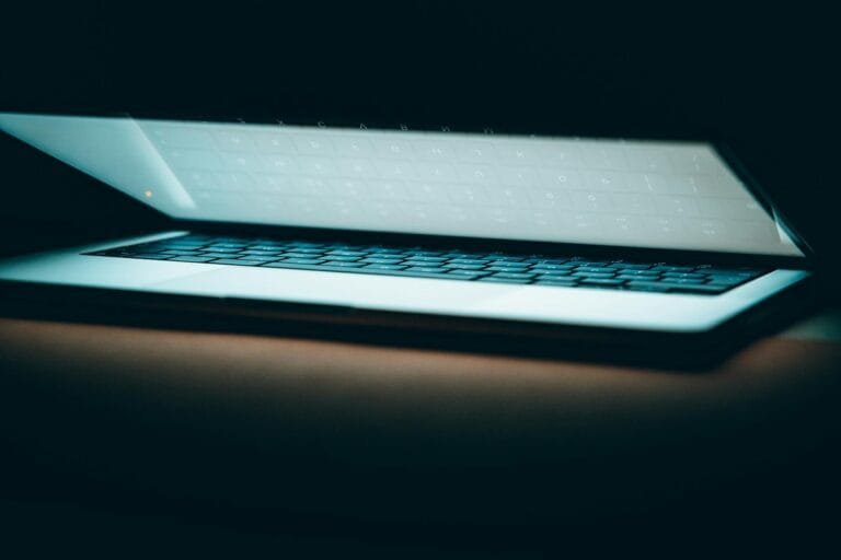 A close-up of a partially open laptop on a wooden surface, displayed in a moody 