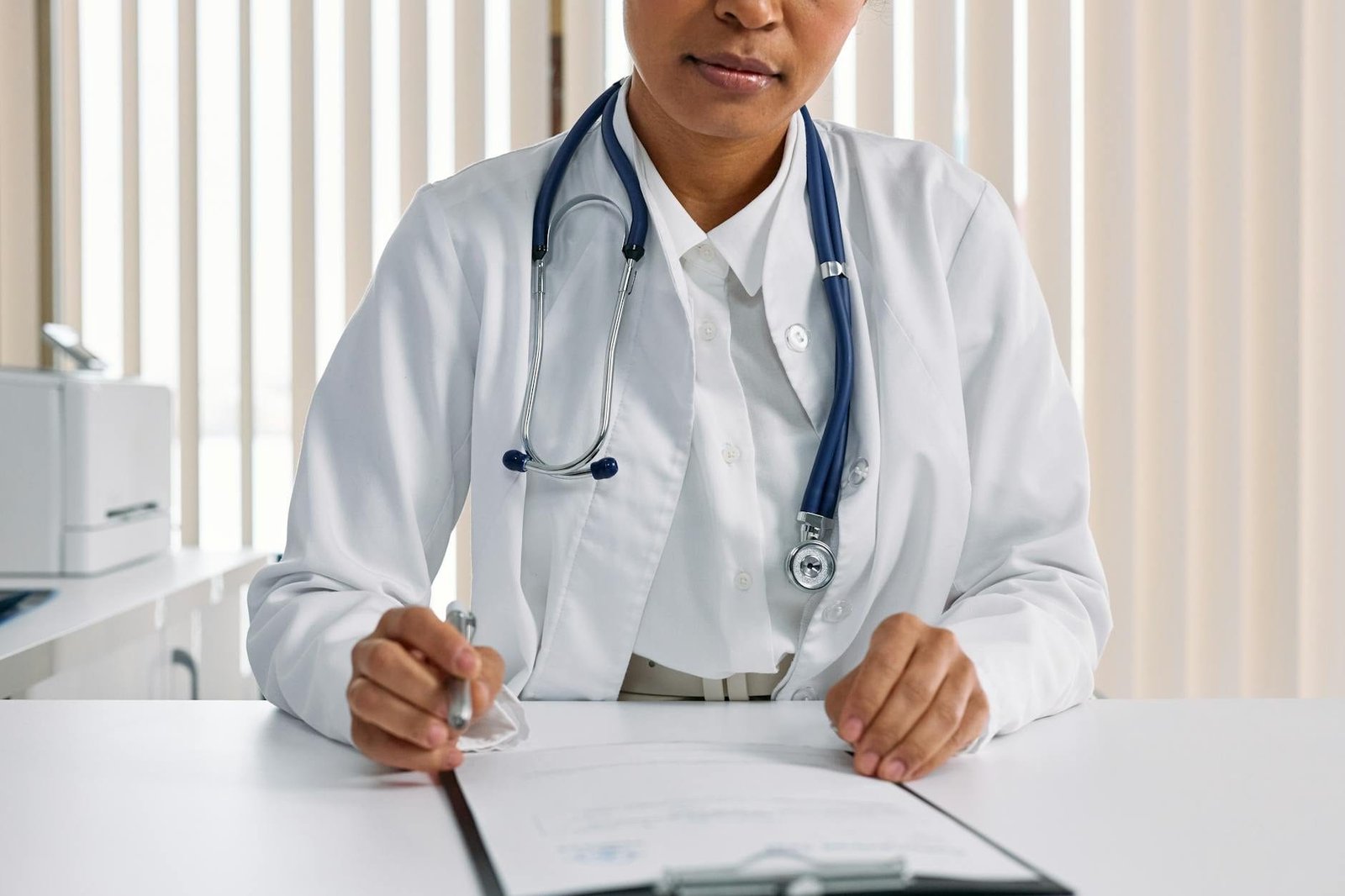 Perícia Médica do INSS: Como se Preparar para o Exame 1 A focused doctor with stethoscope recording patient details in an office setting