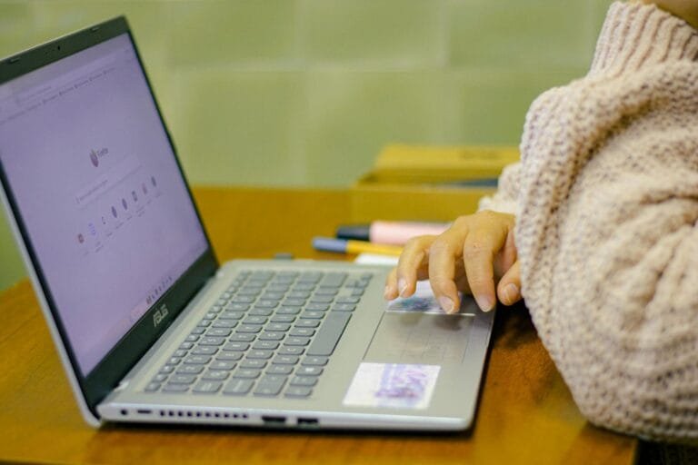 Close-up of a student using a laptop with stationery on a wooden desk in a cozy 