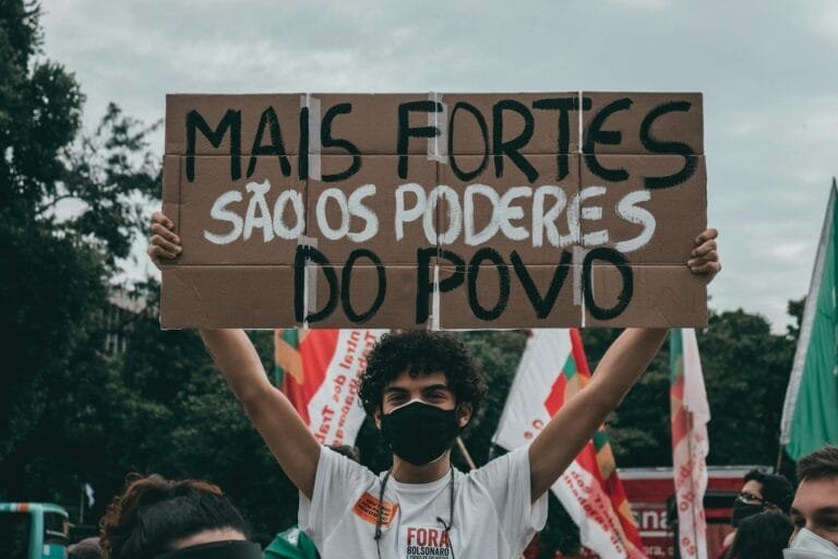 Protester in Rio holds sign saying Mais fortes são os poderes do povo.