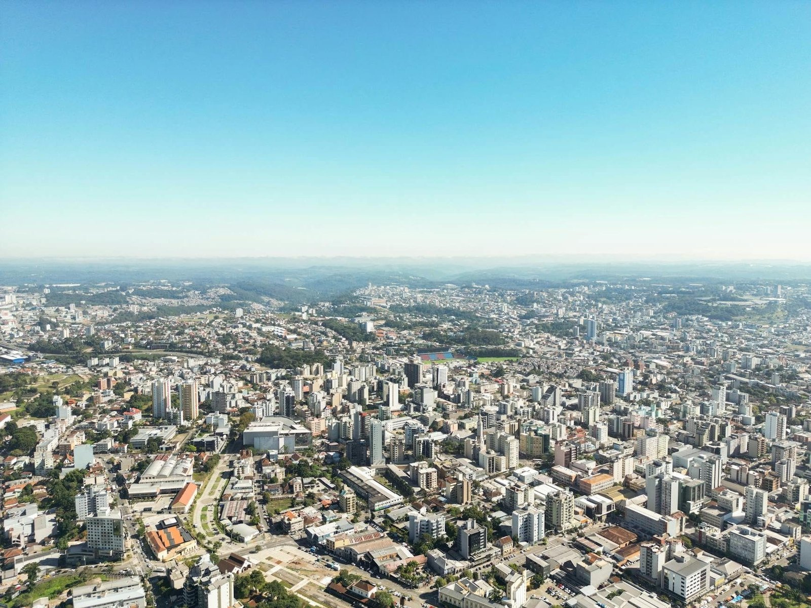 Stunning aerial view of Caxias do Suls urban cityscape under a clear blue sky.