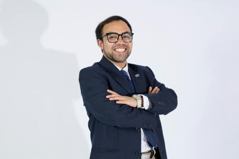 Professional businessman in a suit smiling confidently with arms crossed.