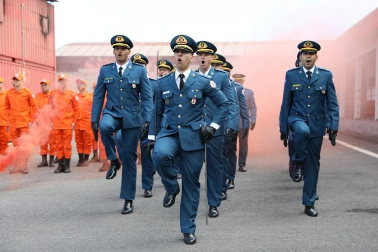 Military personnel march during a parade with firefighters, showcasing disciplin