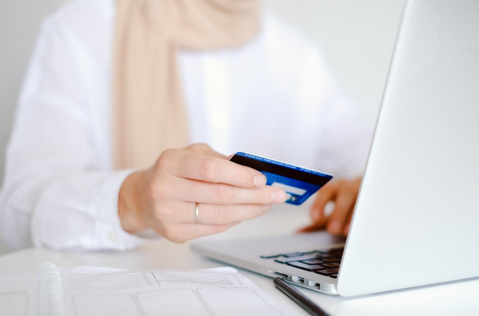 Close-up of a person holding a credit card while using a laptop for online shopp