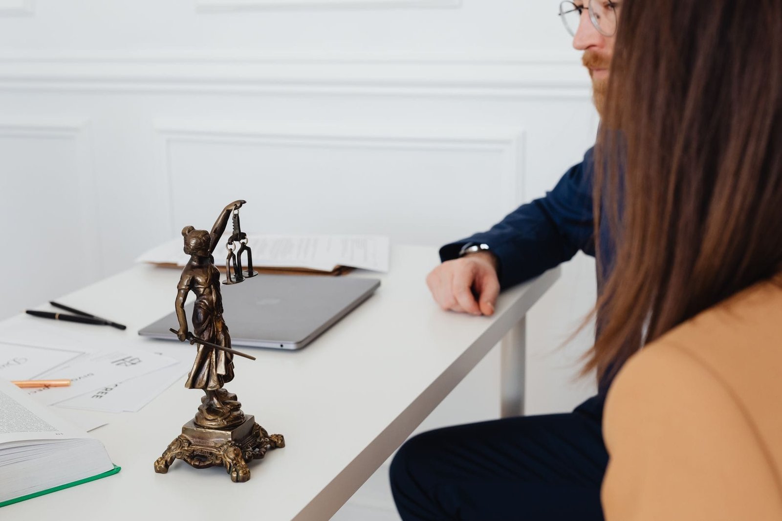 Professional setting with lawyers and Lady Justice statue discussing legal docum