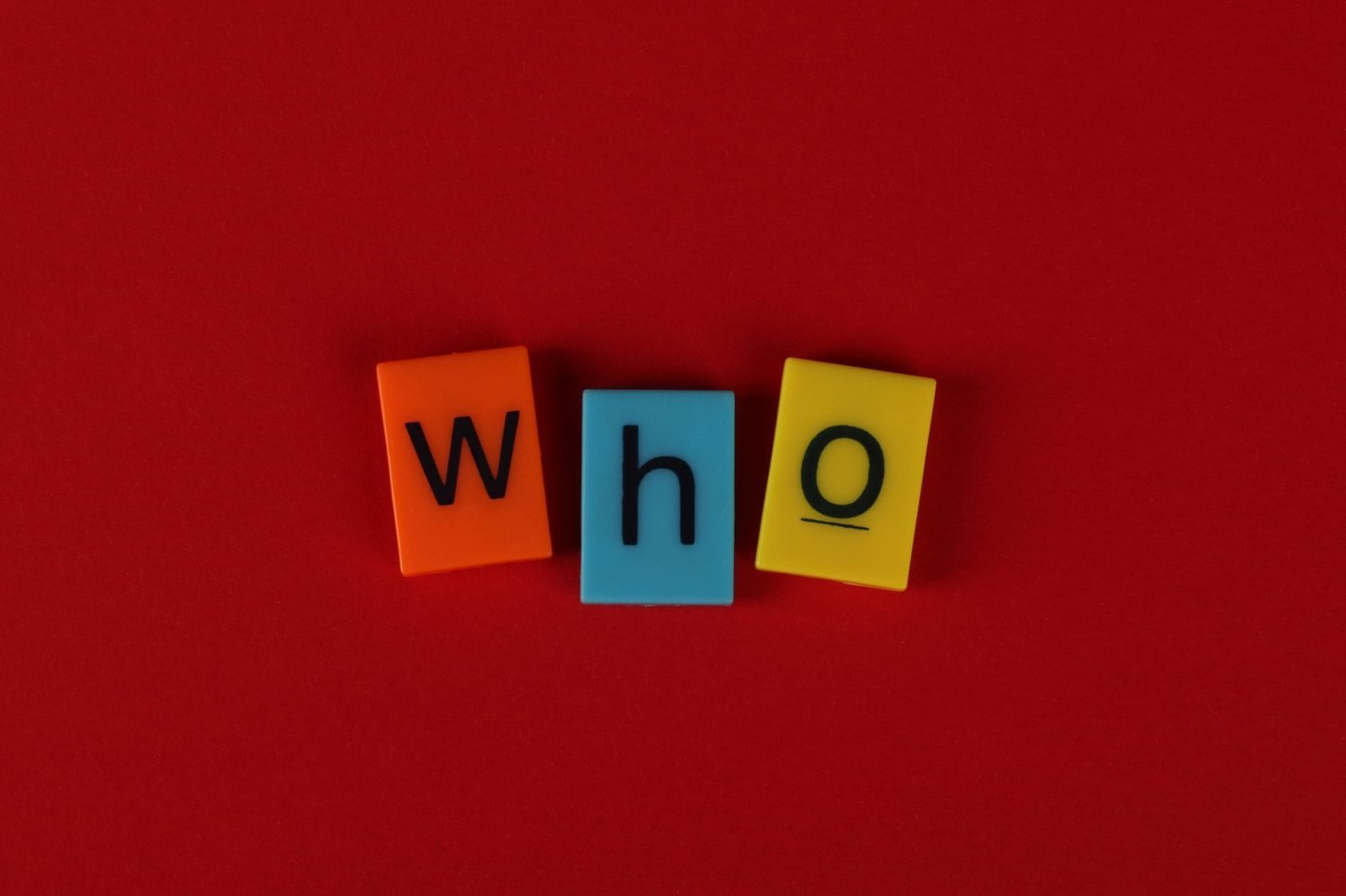 Alphabet blocks forming the word who against a vibrant red backdrop.