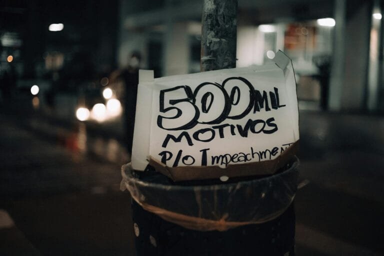 A street pole displaying a protest sign with the message 500 mil motivos p/o im