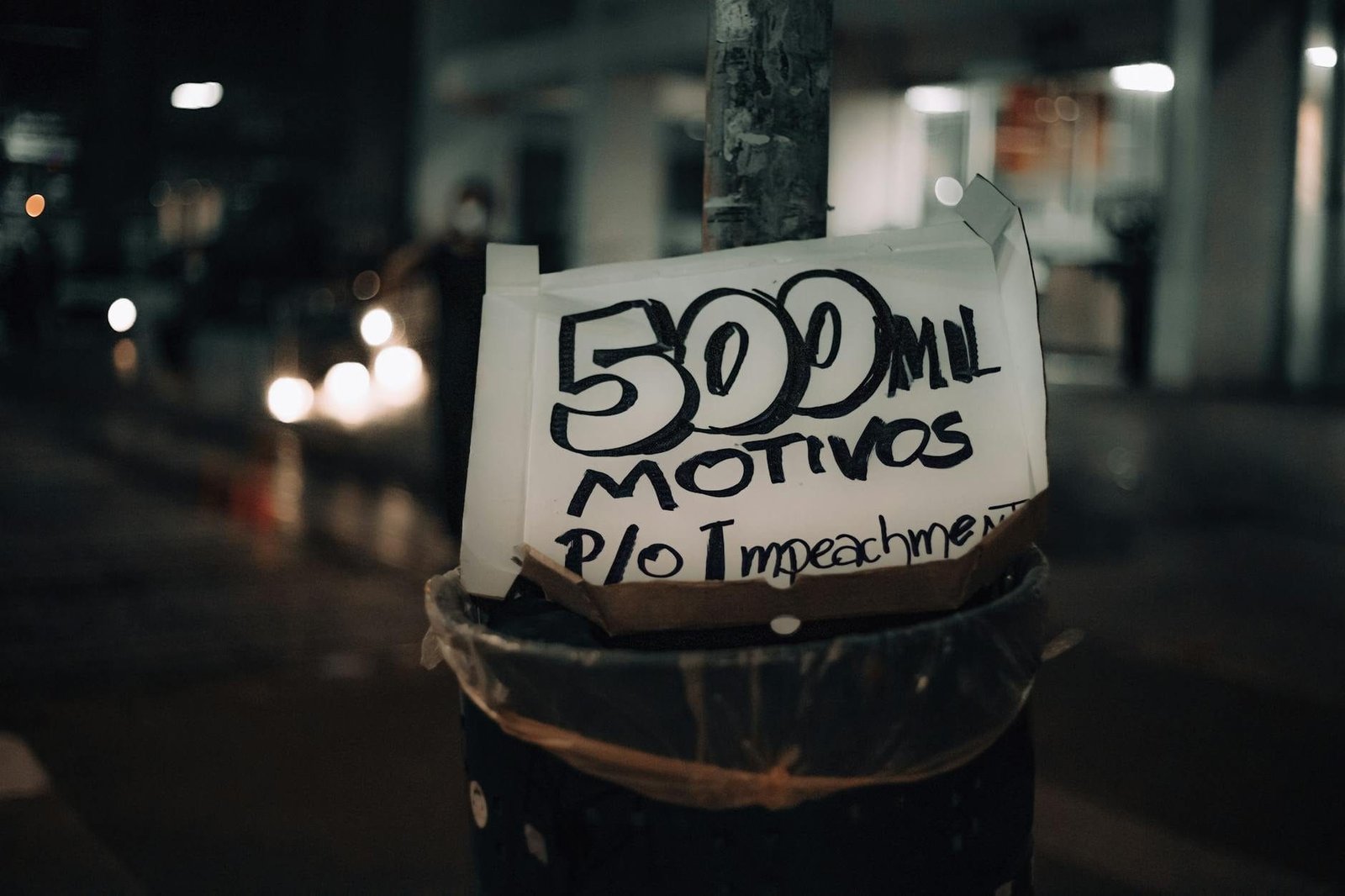 A street pole displaying a protest sign with the message 500 mil motivos p/o im