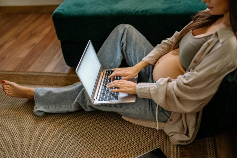 Mãe gestante consulta documentos do INSS no laptop em casa