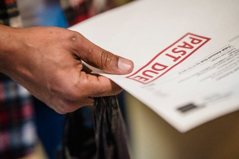 A close-up of a hand holding a document with a Past Due stamp, highlighting financial urgency.