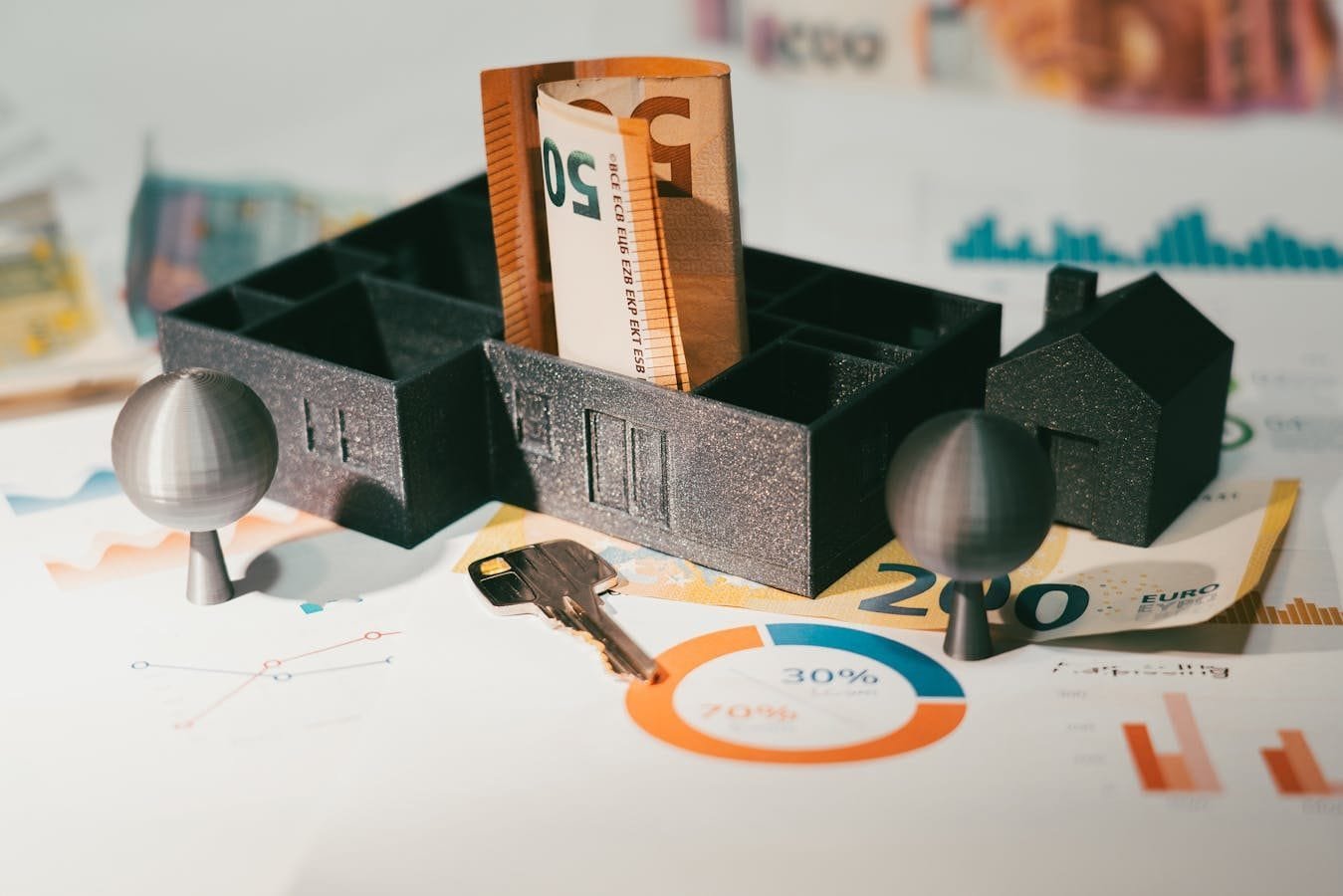 Euro notes with house model and financial charts symbolize real estate investment and economic growth.