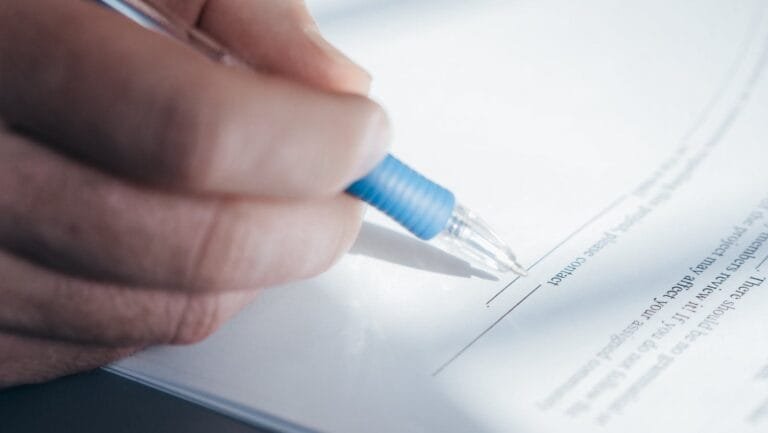 Petição Inicial: O Que Não Pode Faltar em uma Ação 6 A close-up image showing a hand holding a pen while signing a document.